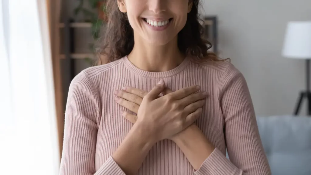 A woman wearing a pink shirt places her hands on her chest as she relieves stress during her therapy in the gta