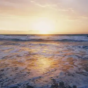 A sea at sunset, waves crashing to the shore symbolizing one to test the waters