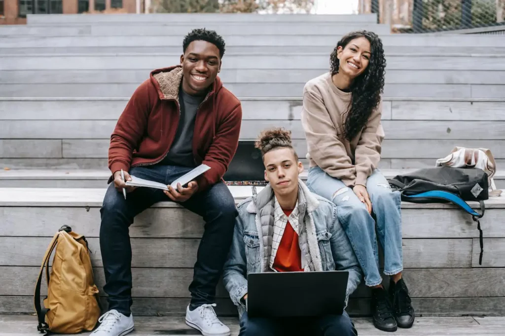 A group of interracial teens sit on a set of strairs