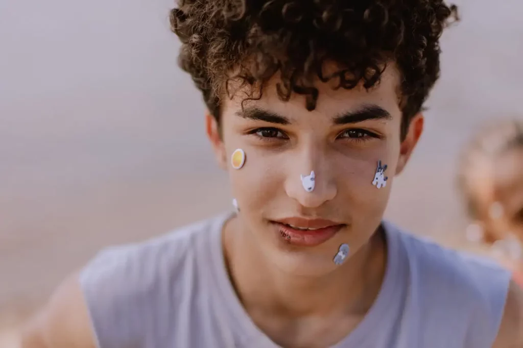 A teen looking into the camera with stickers on his face.